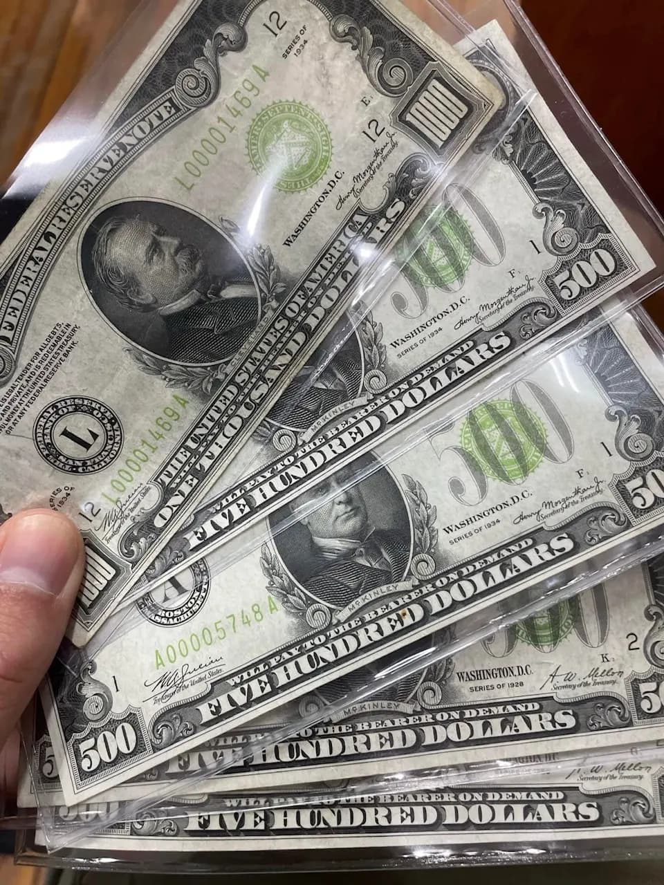 A fanned handful of $500 and $1,000 Federal Reserve Notes from 1928 and 1934 in protective sleeves