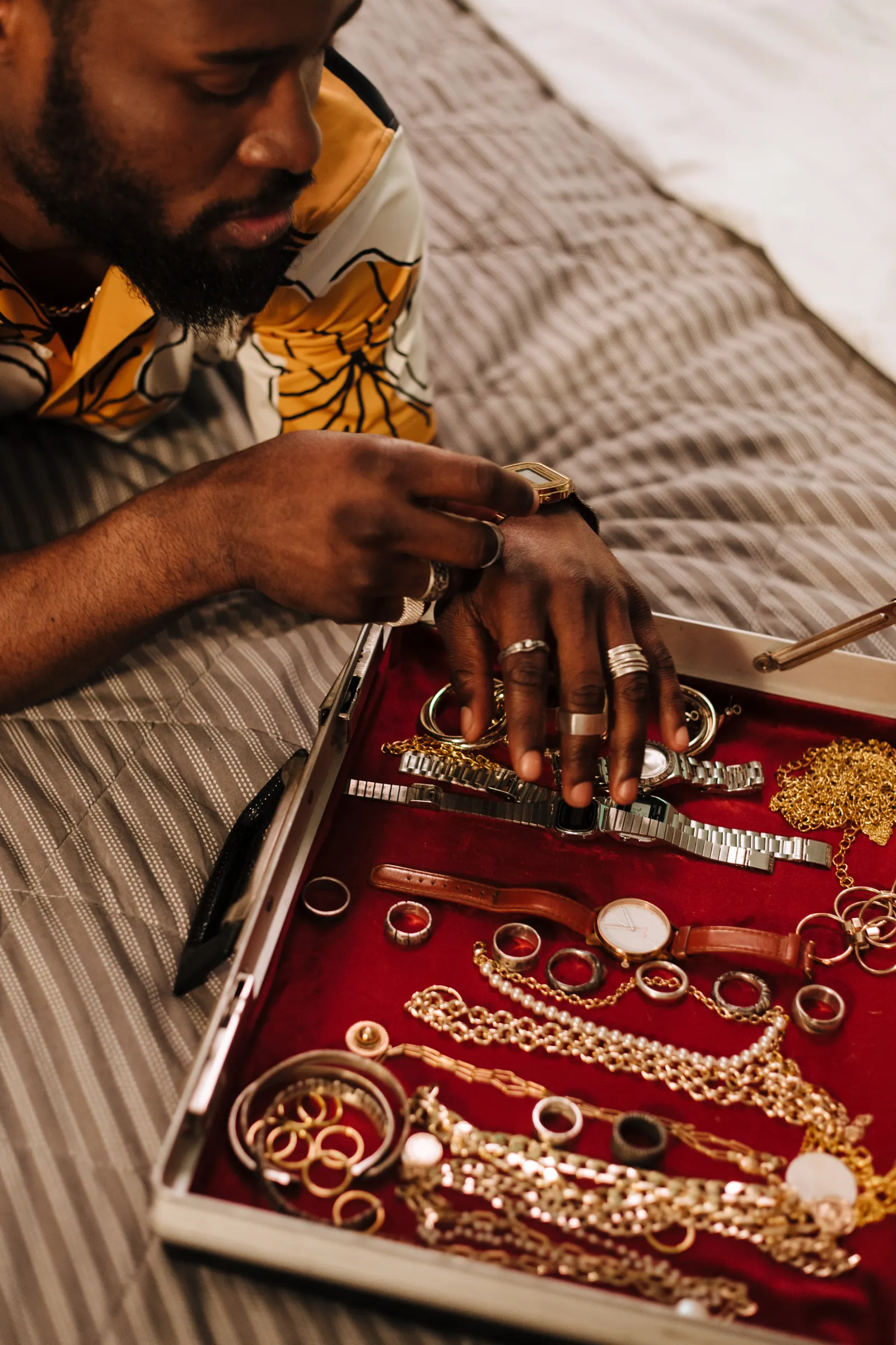 Hands sorting through a tray of mixed gold jewelry and watches
